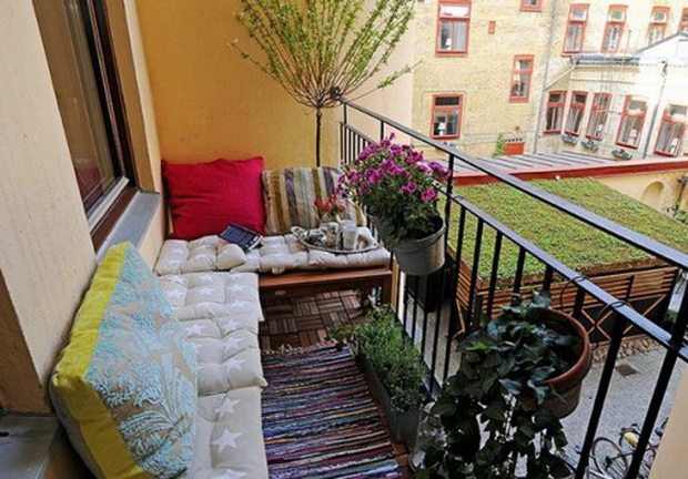 интерьер открытого балкона с подушками и цветами
