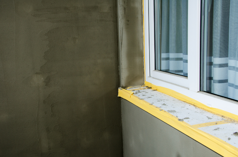 Semifinished repairing of balcony, gray plaster and dirty white window.